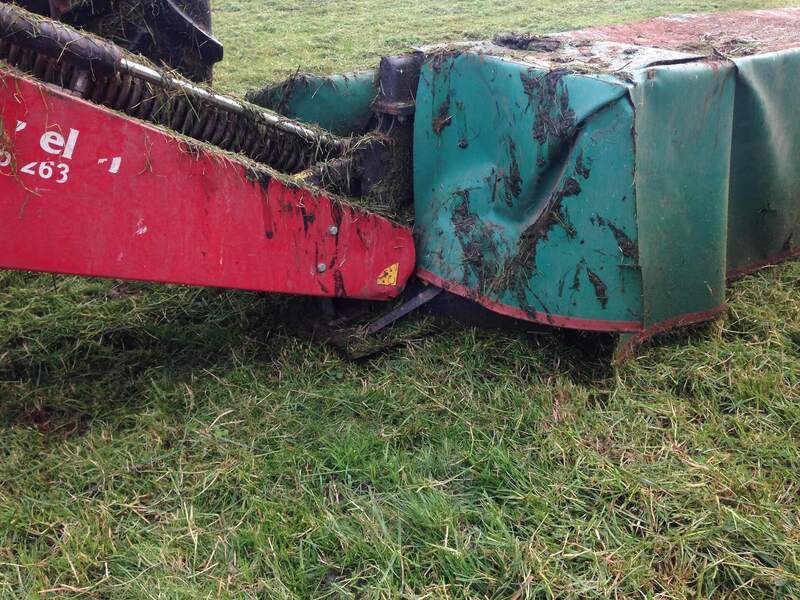 Pasture mower splattered with dung and grass clippings after topping.